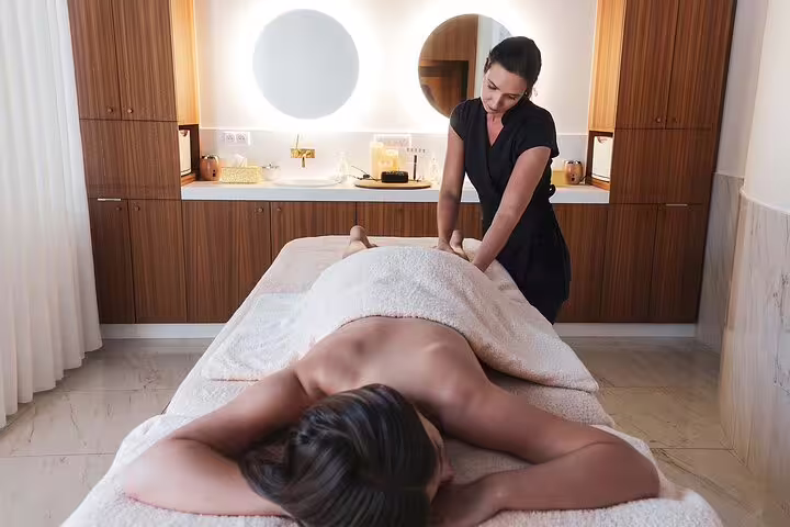 Therapist giving full-body massage in Cleopatra Deluxe VIP spa package with sauna and jacuzzi access