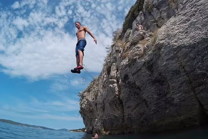 Cliff jumper leaping from a rocky sea cliff on a Split deep water solo and cliff jumping tour