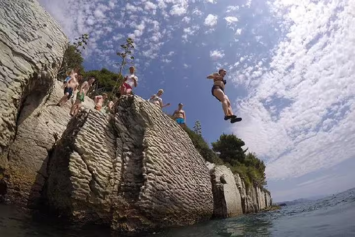 Group cliff jumping into Adriatic from rocky coast on Split deep water solo adventure tour Croatia