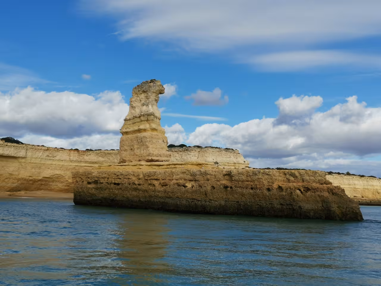 Stunning golden limestone sea stack rising from calm Algarve waters on a luxury catamaran tour from Albufeira
