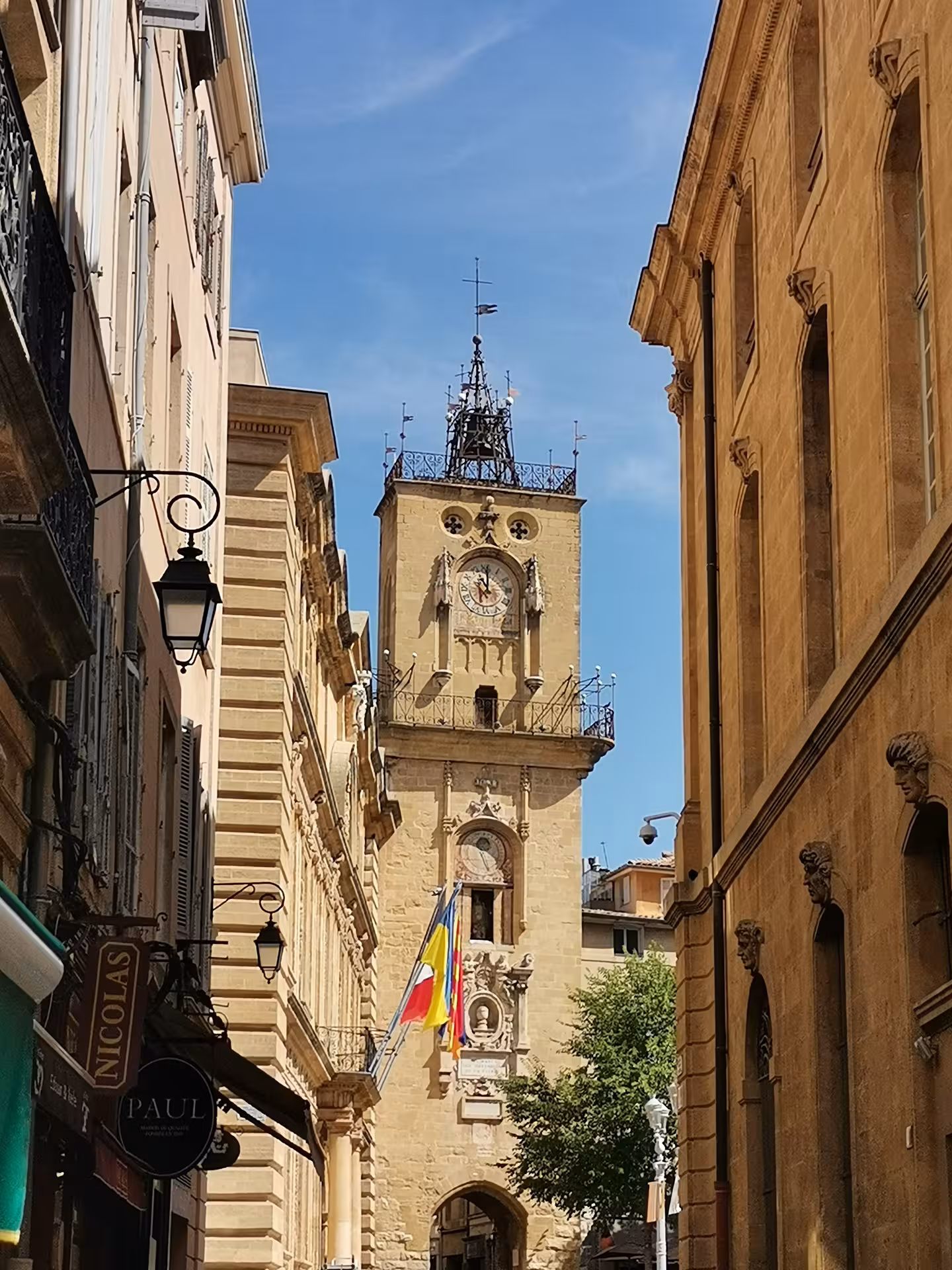 Clock tower in a sunlit Provençal old town street, cultural stop on an 11-day Christian heritage tour in Provence