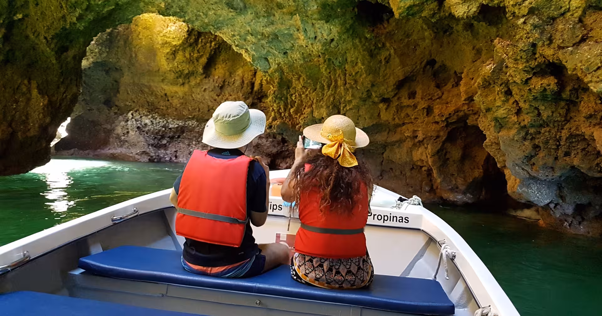 Tourists in life jackets on a small boat cruising through Ponta da Piedade sea caves during a coastal trip from Lagos