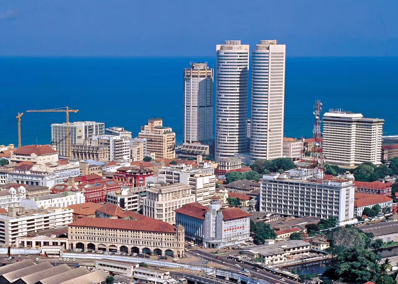 Aerial view of a coastal cityscape with modern skyscrapers and a vibrant urban atmosphere near the ocean.
