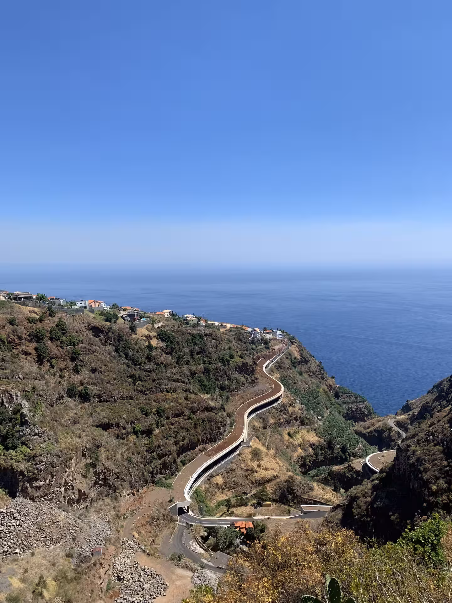 Panoramic view of winding coastal road along steep cliffs, ideal for private group tours seeking stunning ocean vistas.