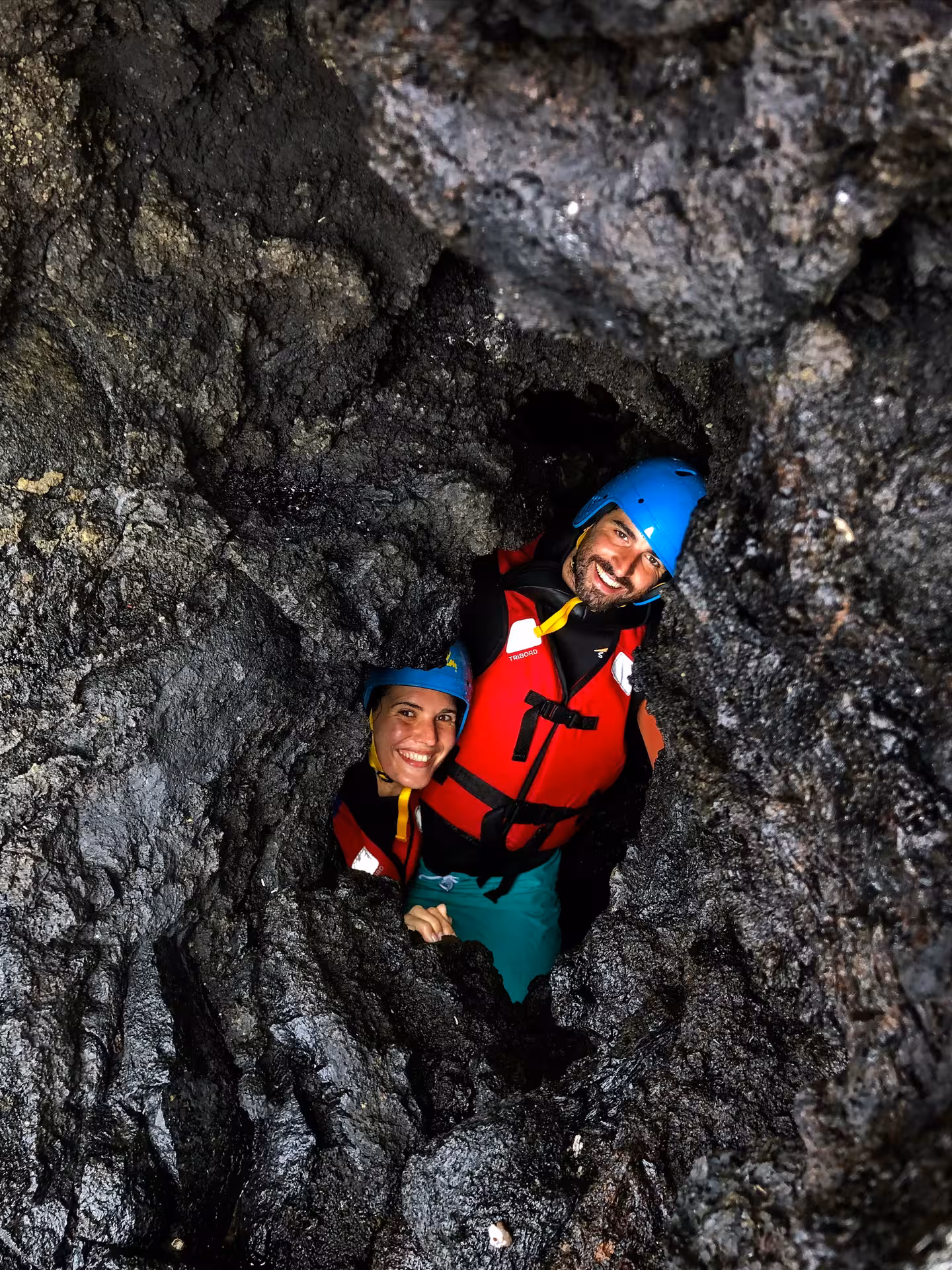 COASTEERING Freshman adventure as two participants in helmets and buoyancy aids explore a rocky sea cave