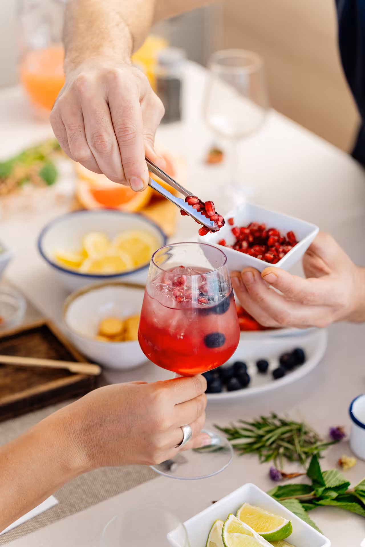 Cocktail masterclass guest garnishing a berry spritz with pomegranate seeds at a hands-on mixology class