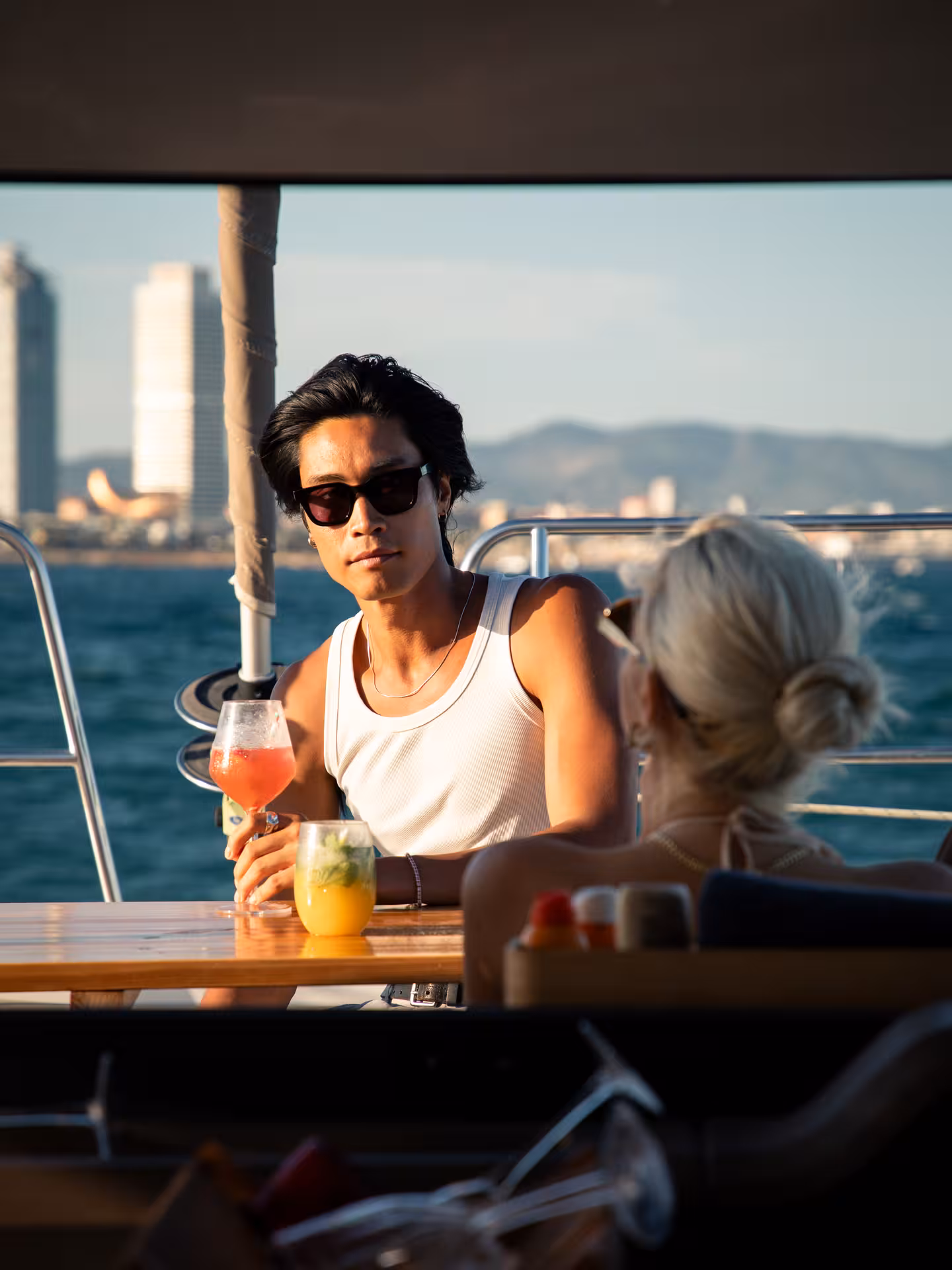 Guests enjoying cocktails on a boat with sea and skyline views, ideal cocktail masterclass and mixology experience