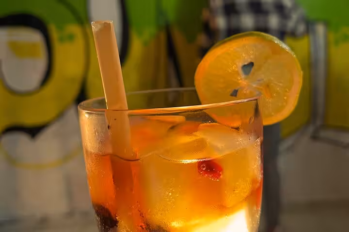 Close-up cocktail with orange slice and ice in front of street art at the Sip and Spray graffiti tour