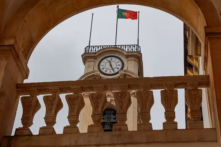 Clock tower adorned with the Portuguese flag, a highlight of Coimbra's iconic architectural tour.