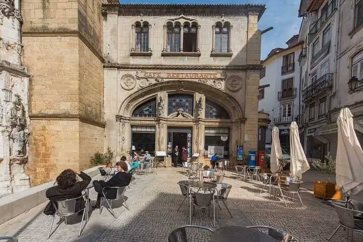 Charming Coimbra café scene with patrons enjoying outdoor seating against historic architecture backdrop.