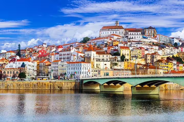 Scenic view of Coimbra's hillside cityscape and bridge over the Mondego River, ideal for a Fátima & Coimbra day tour.