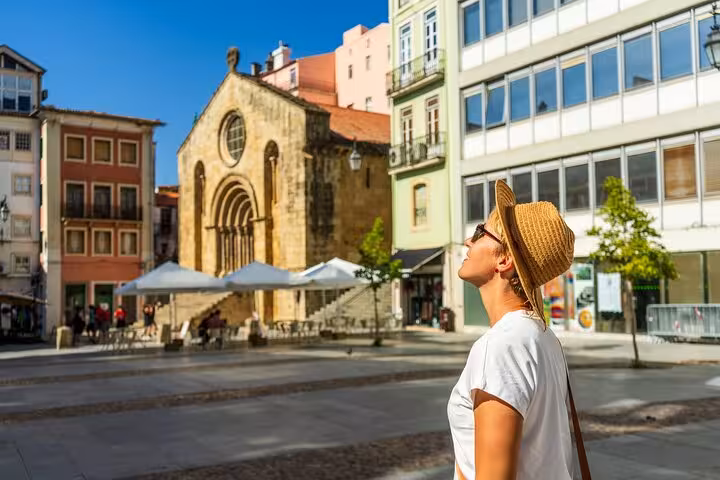 Tourist enjoying a sunny day in Coimbra's historic square, highlighting the charm of Portugal's medieval architecture.