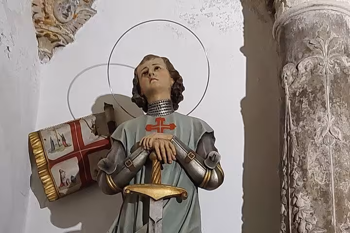 Statue of a knight with a sword and halo in a historic Coimbra church, featured in a private walking tour.