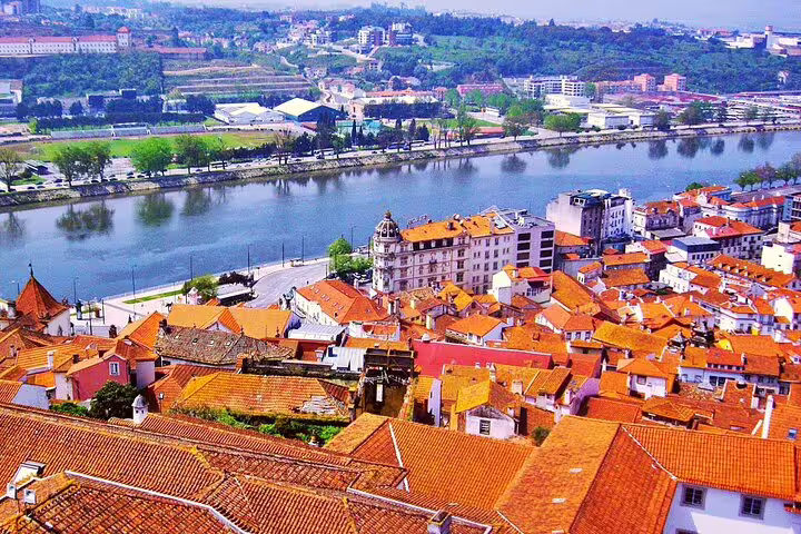 Aerial view of Coimbra's charming rooftops along the Mondego River, highlighting a scenic stop on the Porto to Lisbon journey.