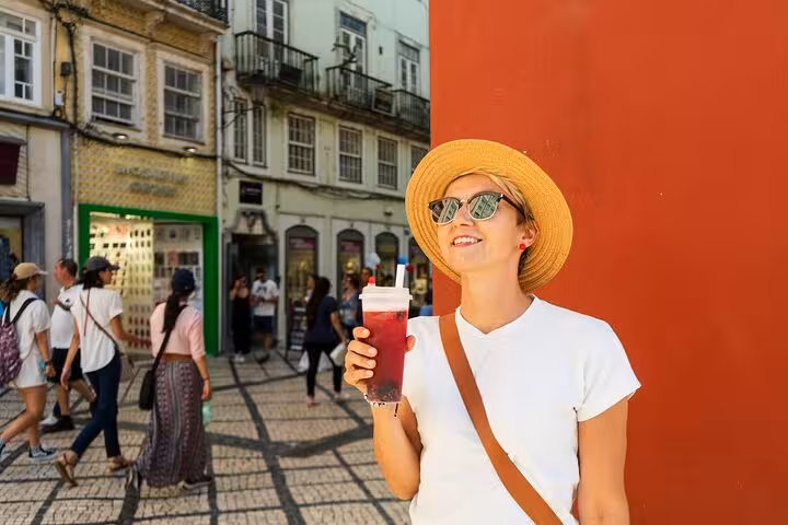 Smiling tourist enjoying a drink in Coimbra's vibrant historic center during a private city walk tour.