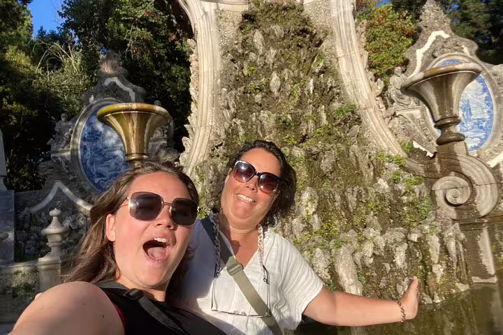 Friends posing by ornate fountain in Coimbra on a self-guided scavenger hunt walking tour with city highlights