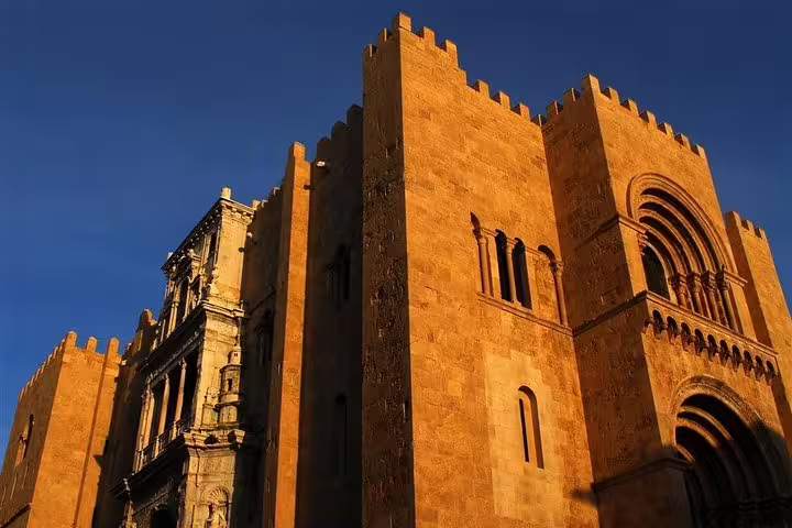 Sunlit medieval architecture of Coimbra's Sé Velha cathedral, featured in the Tomar and Coimbra private tour from Lisbon.