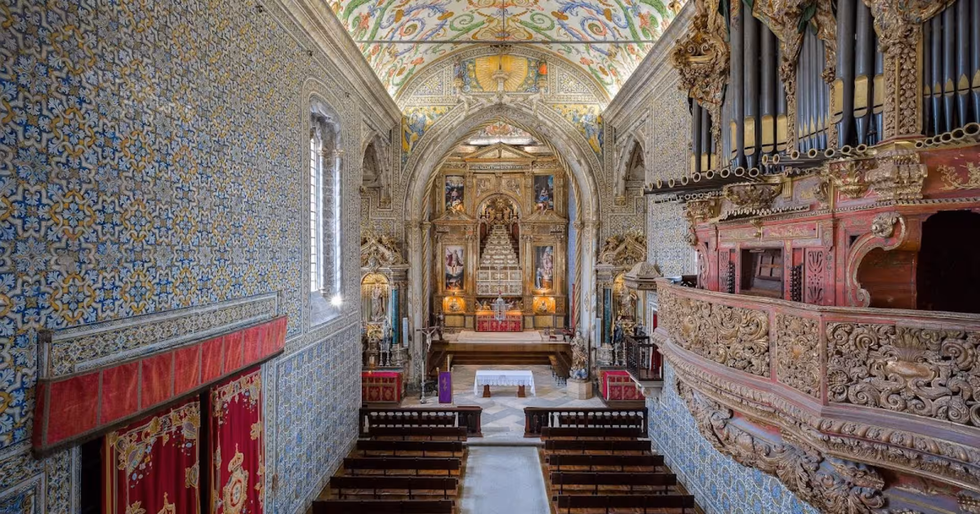 Explore the ornate interior of Coimbra University's Chapel of São Miguel with elaborate azulejos and a grand organ.