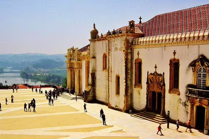 Scenic view of Coimbra University courtyard with historic architecture and tourists exploring the area in Portugal.