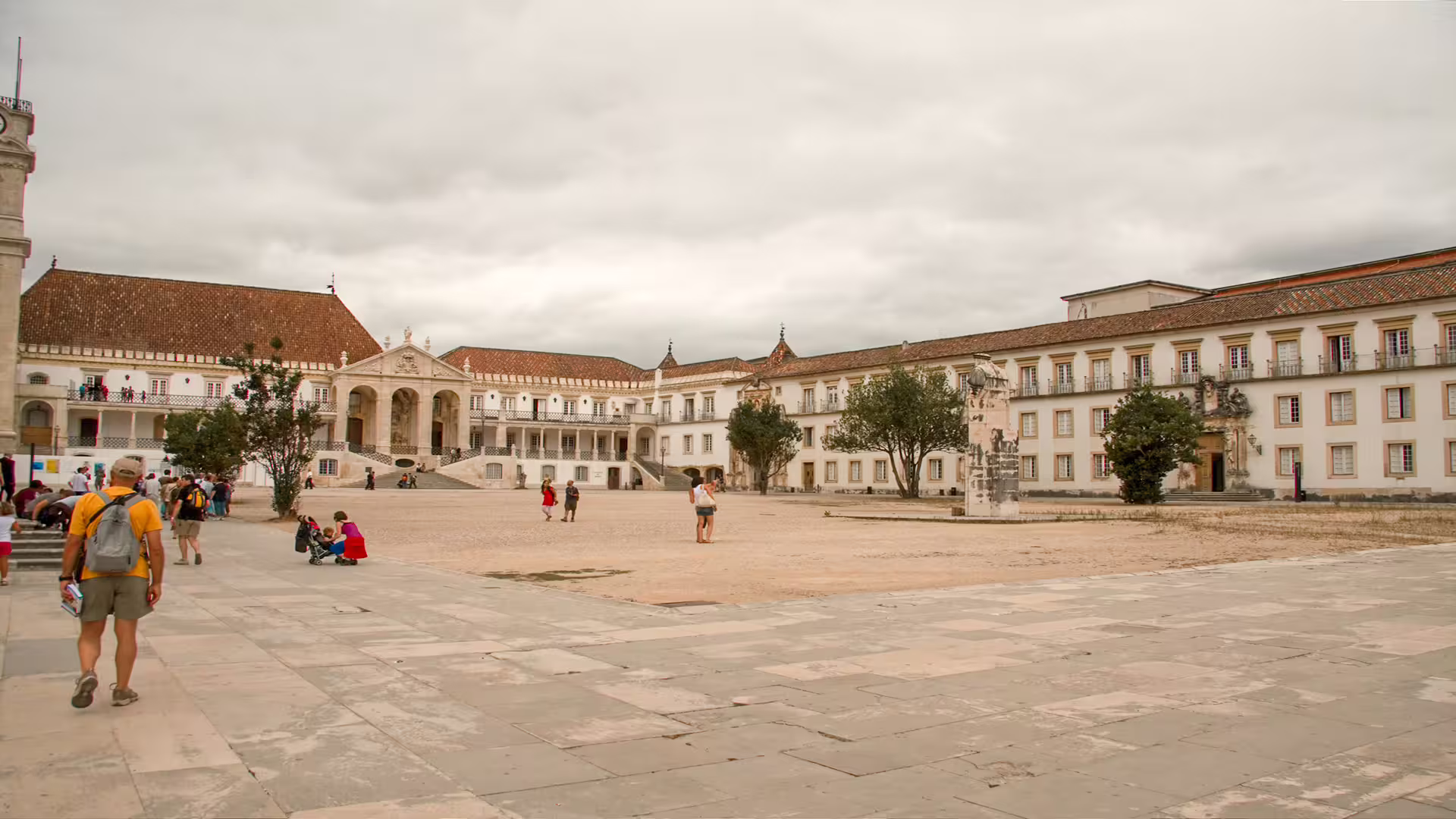 Tourists exploring the historic courtyard of the University of Coimbra, a highlight of the private tour to Portugal's ancient sites.