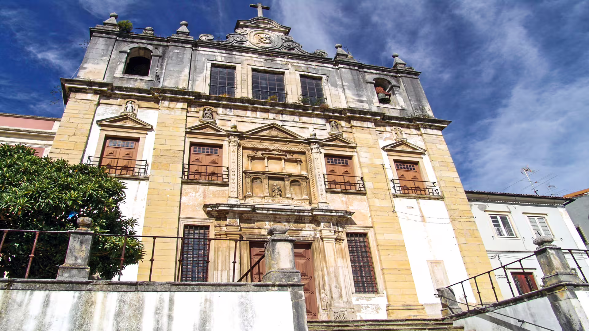 Historic facade of a Coimbra building under a blue sky, part of the University of Coimbra and ancient Roman city tour.