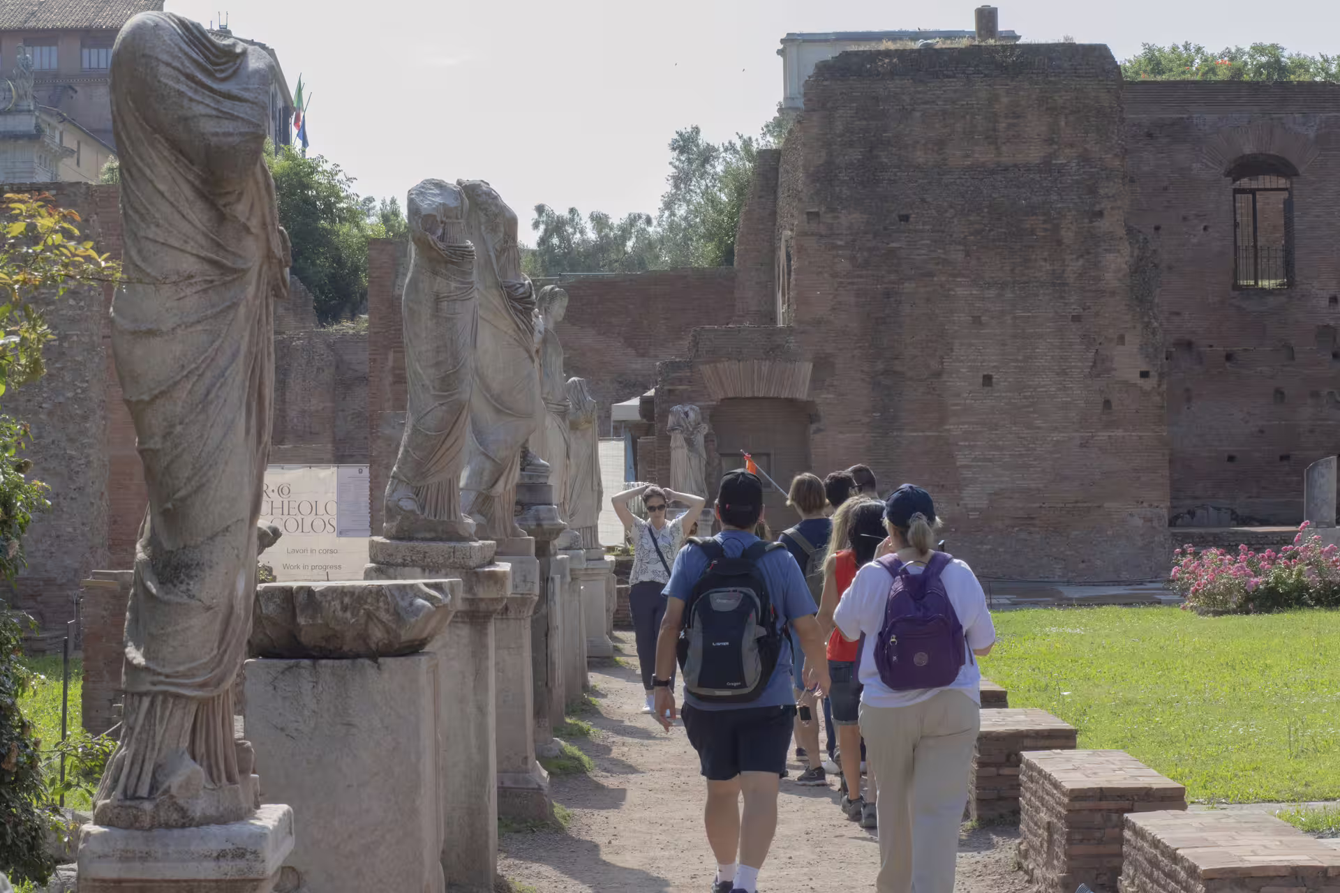 Grupo caminando entre estatuas y ruinas en el Foro Romano durante tour guiado Coliseo, Foro y Palatino