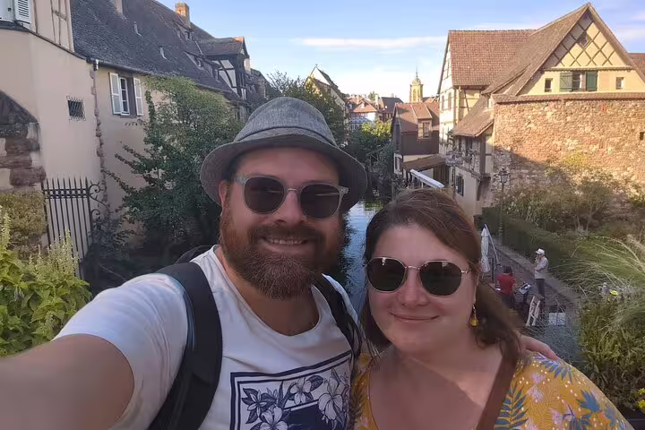Couple selfie by Colmar’s Little Venice canal, ideal photo stop on a self-guided scavenger hunt tour