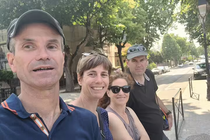 Friends smiling on a Colmar scavenger hunt, walking a leafy street during a self-guided city tour