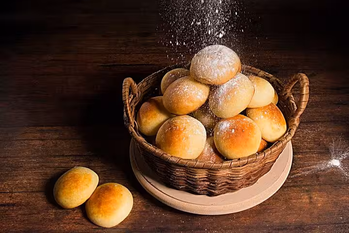 Freshly baked Colombian buns dusted with flour in a rustic basket, highlighting Medellín's street food delights.