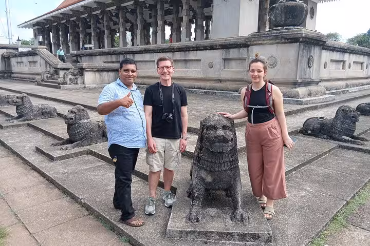Guests pose with stone lion statues at Gangaramaya Temple on a Colombo City Tuk Tuk sightseeing tour