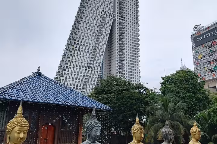 Colombo city tour view of a Buddha temple pavilion with modern skyline, seen on Royal City Tuk Tuk ride