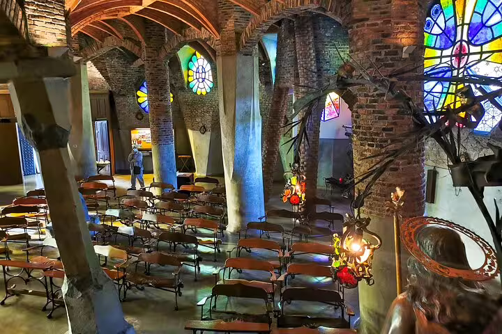 Interior of Colonia Güell's Gaudí-designed crypt with stained glass windows and unique architecture on a private skip-the-line tour.
