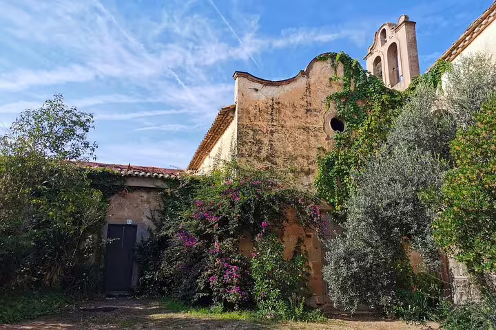 Historic Colonia Güell building covered in lush greenery under a clear blue sky, featured in skip-the-line private tour.