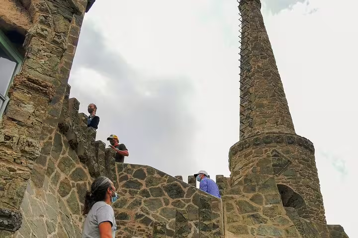 Visitors explore the historic architecture of Colonia Güell, featuring intricate stonework and a unique spire, on a guided tour.