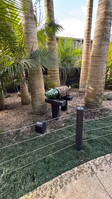 Colorful crocodile sculpture amidst tropical trees and greenery, perfect for a unique outdoor art tour experience.