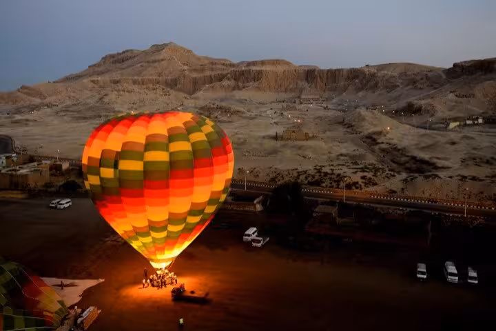Colorful hot air balloon glowing at dawn during desert launch, lifetime experience balloon ride adventure