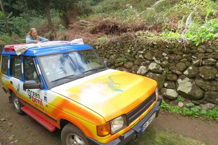 Colorful jeep on a scenic trail in Madeira Islands, offering a full day guided tour through lush landscapes and rugged terrain.