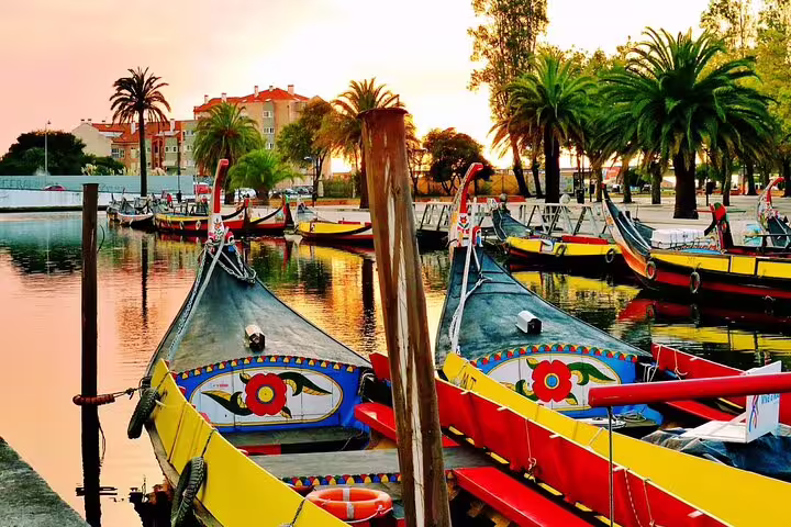 Colorful moliceiro boats docked at sunset in Aveiro, highlighting the vibrant start of a Costa Nova tour from Porto.