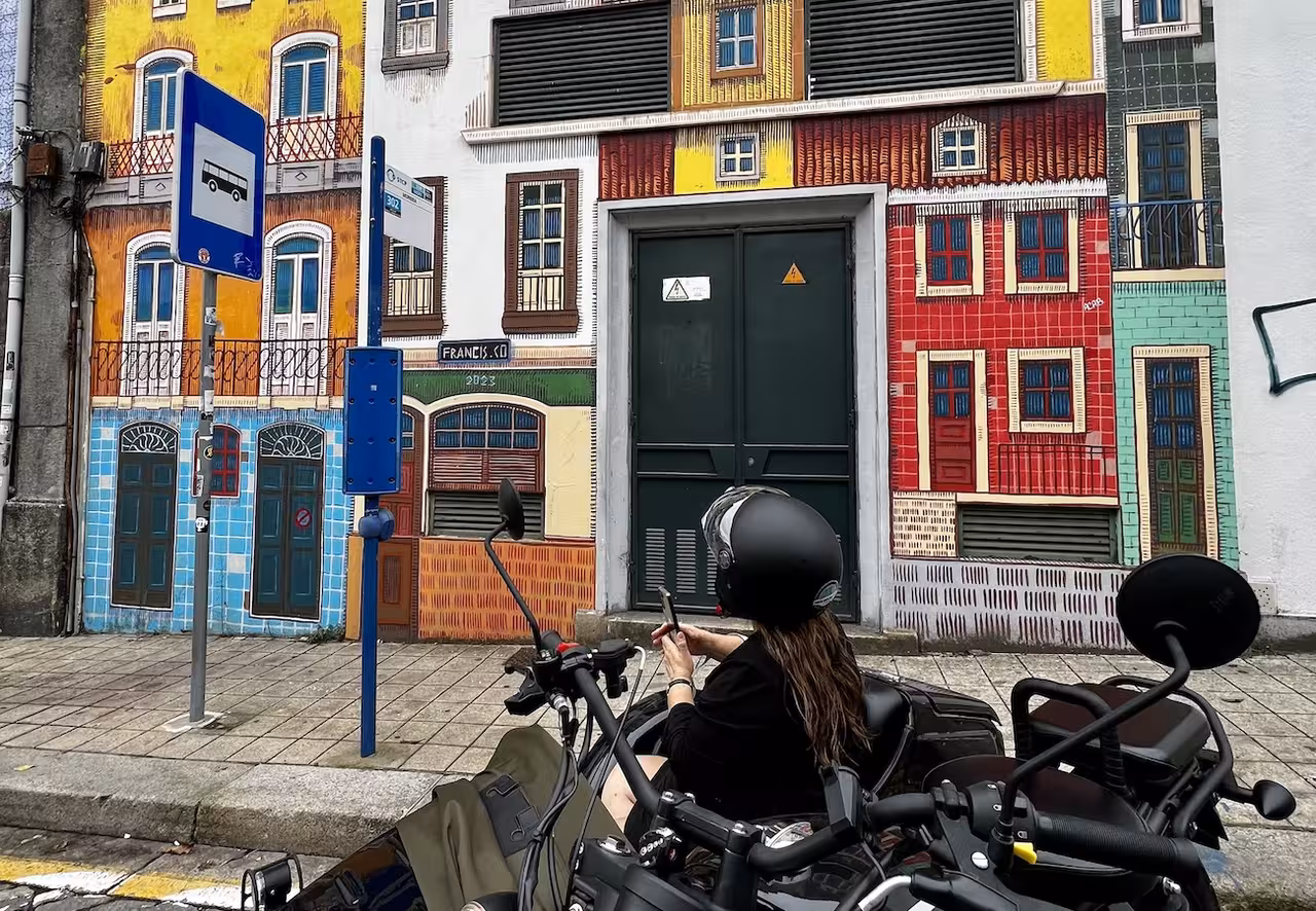 Colorful painted building facade mural stop on a street art tour, with a rider photographing urban art