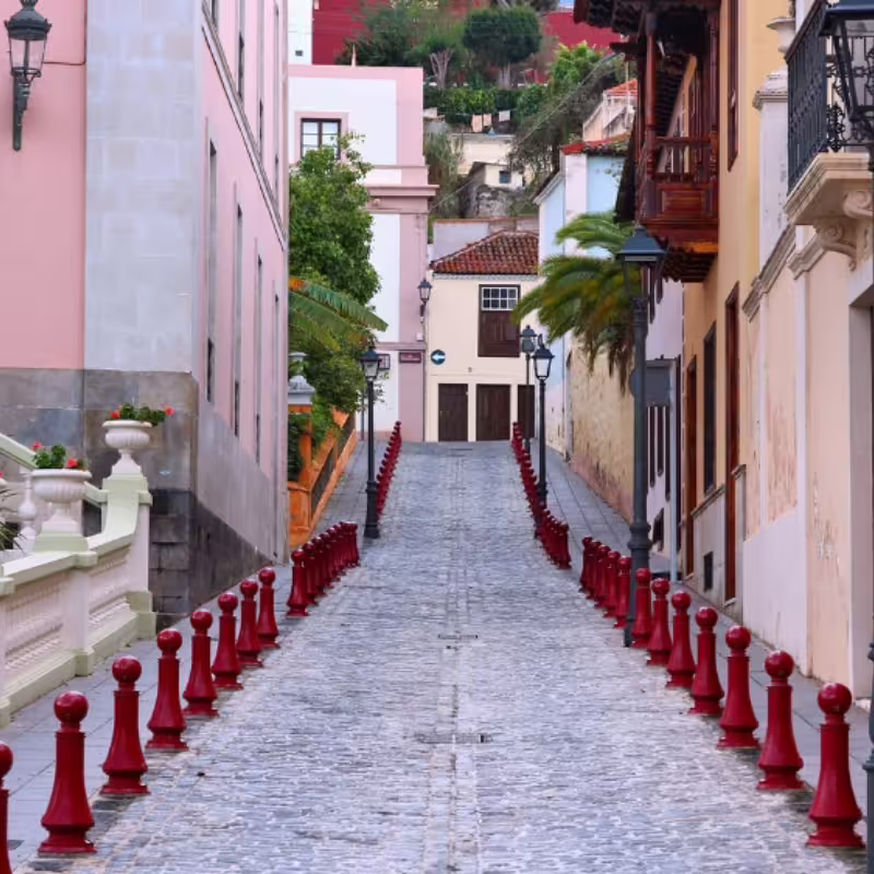 Charming cobblestone street lined with colorful buildings and red posts, ideal for exploring on cruise excursions.