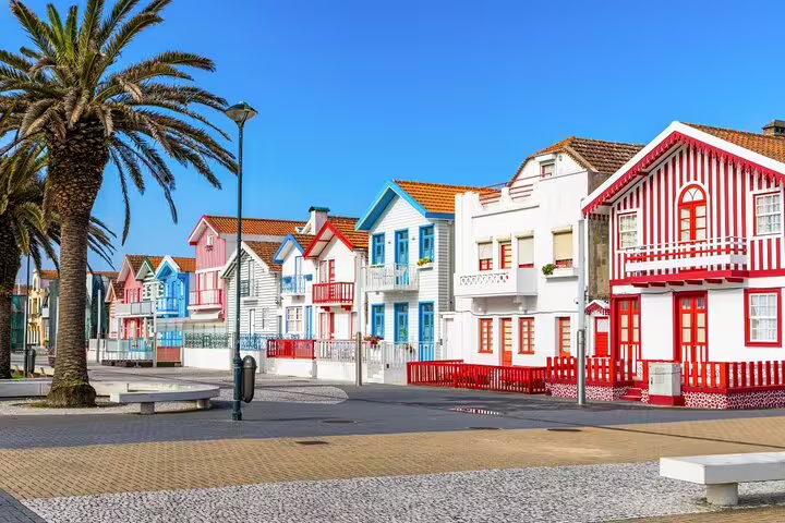 Colorful striped houses line the sunny promenade in Costa Nova, Aveiro, perfect for a scenic stop on your private tour from Lisbon.