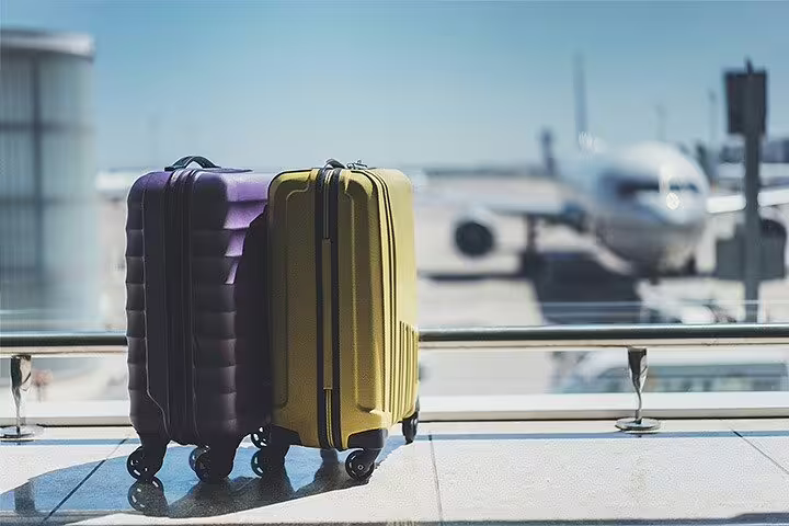 Colorful suitcases at airport terminal window ready for private transfer from Rome to Positano on Amalfi Coast