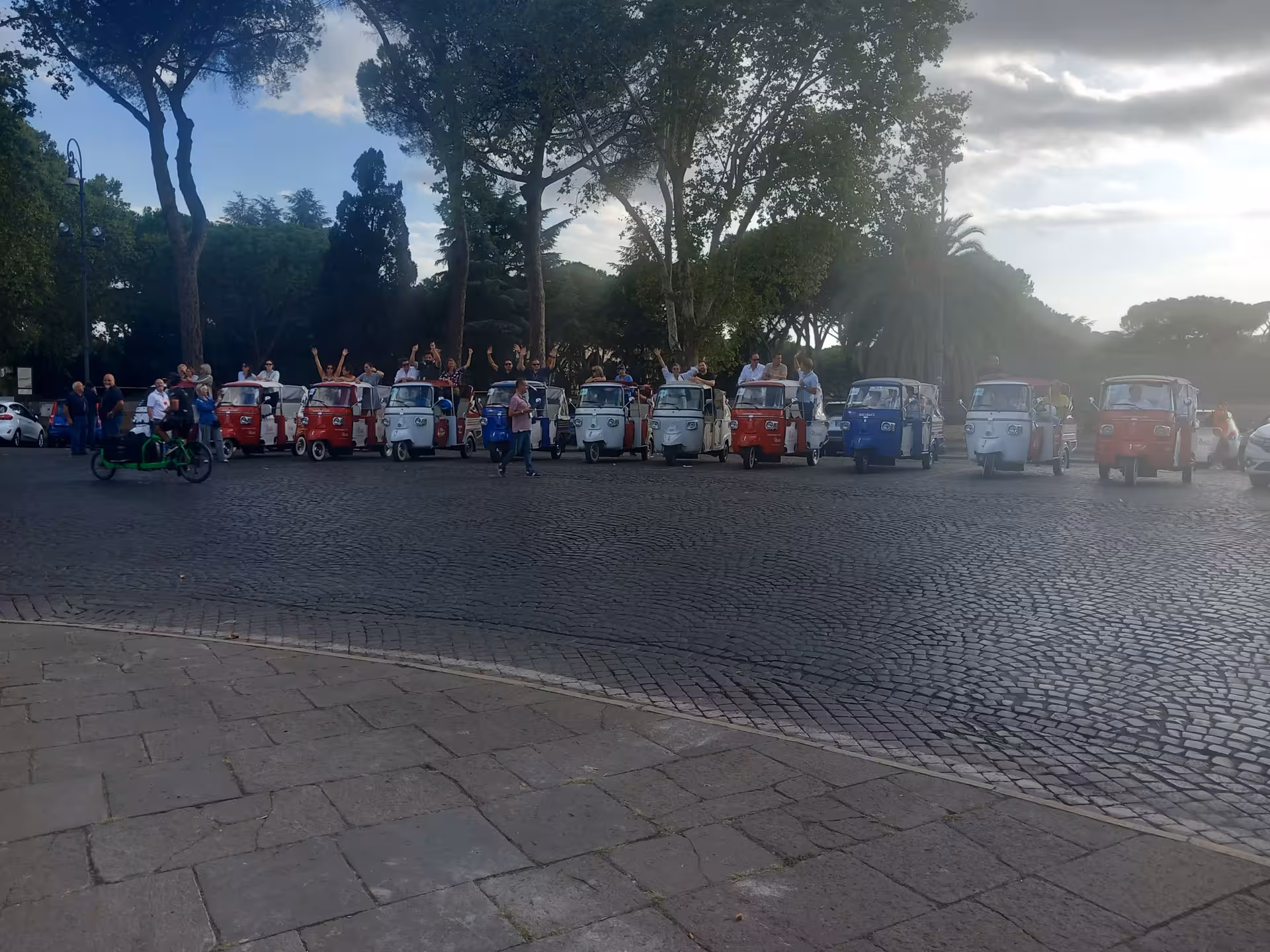 A vibrant lineup of colorful tuk-tuks with excited tourists in Rome, showcasing a unique city tour experience.