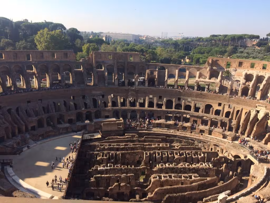 Aerial view of the Colosseum interior, showcasing its ancient architecture and vibrant atmosphere on a sunny day.
