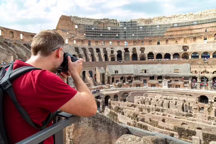 Traveler photographing the ancient arena floor and tiers of Rome’s Colosseum during a private guided tour with skip-the-line access
