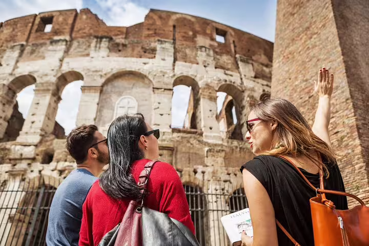 Local expert guide leading two travelers outside the Colosseum, beginning a private arena floor tour in Rome