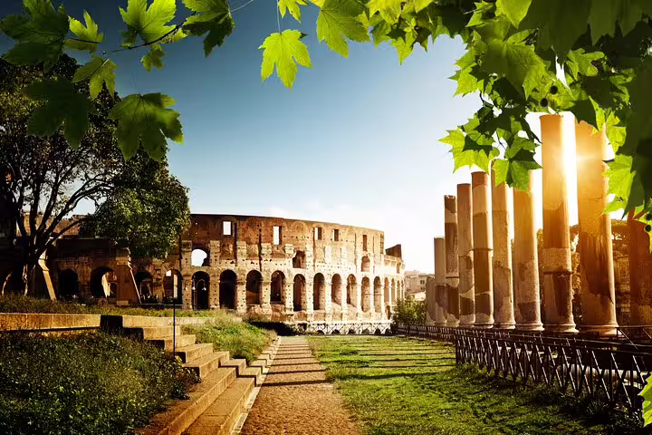 Sunlit Colosseum and Roman Forum ruins framed by green leaves on a private arena floor tour with expert guide in Rome