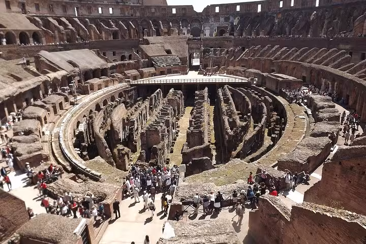 Interior view of the Colosseum arena filled with tourists exploring the historic amphitheater.