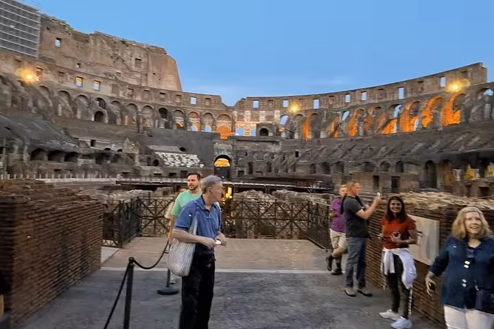 Evening tour participants enjoy the illuminated Colosseum, capturing the ancient arena's majestic beauty in Rome.