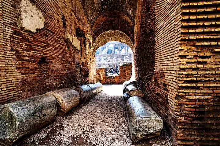 Ancient brick corridor and fallen marble columns inside the Colosseum, seen on a VIP gladiators arena floor guided tour